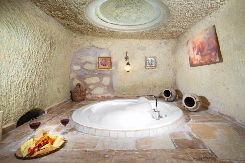 a large tub in a room with two glasses of wine at World Cave House - Hotel & Swimming Pool in Ürgüp