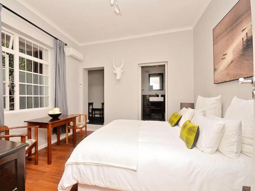 a white bedroom with a large bed and a table at Cactusberry Lodge in Cape Town