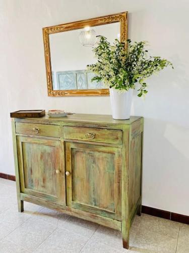 a wooden dresser with a mirror and a plant on it at La casa di Regina in Tronzano Vercellese