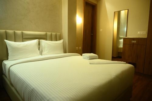 a bedroom with a large bed with white sheets and pillows at The Marwar in Cuttack