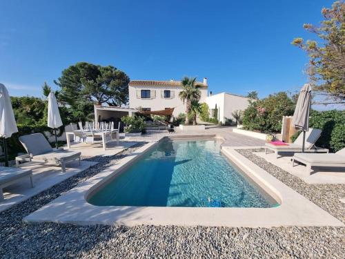 - une piscine dans une cour avec des chaises et des parasols dans l'établissement Mas au Bord de L'étang, à Vic-la-Gardiole