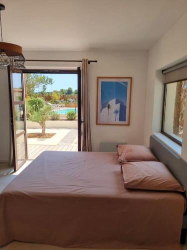 une chambre avec un grand lit et une grande fenêtre dans l'établissement Mas au Bord de L'étang, à Vic-la-Gardiole