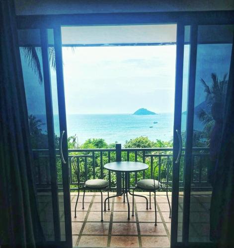 einen Balkon mit einem Tisch und Stühlen sowie Meerblick in der Unterkunft Mae Haad Sunset 2 in Ko Tao