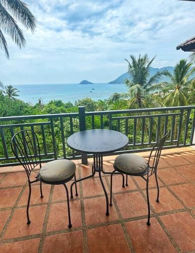 einen Tisch und Stühle auf einem Balkon mit Meerblick in der Unterkunft Mae Haad Sunset 2 in Ko Tao