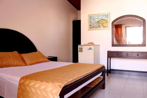 - une chambre avec un lit, une commode et un miroir dans l'établissement Alborada Hotel Melgar, à Melgar