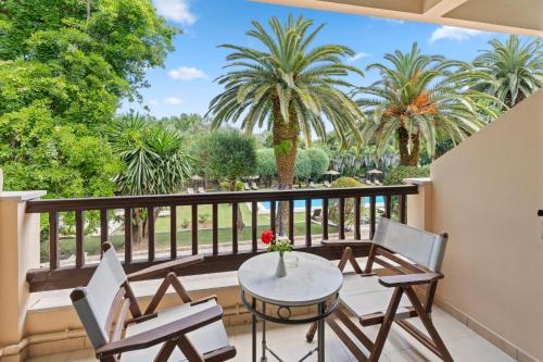a balcony with a table and chairs and palm trees at Fiori Hotel in Gouvia