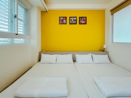 a bedroom with a bed with a yellow wall at 運河十六 海港景觀整層主臥房Canal16 HarborView Studio in Tainan
