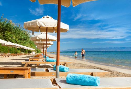 a beach with tables and umbrellas and people in the water at Camvillia Resort Messinia in Vounaria