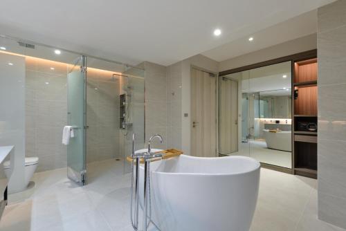 a bathroom with a white tub and a shower at GM Estate Hotel and Executive Apartments Sukhumvit 20 in Bangkok