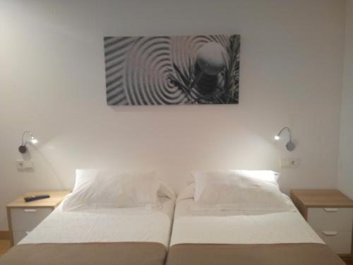 1 dormitorio con 1 cama y una pintura en la pared en Pensión Sarasate en Pamplona