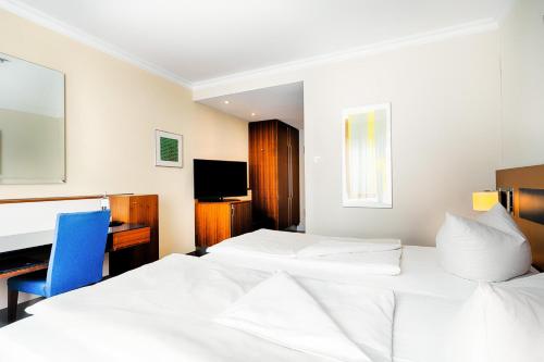 ein Hotelzimmer mit zwei Betten und einem Schreibtisch in der Unterkunft Welcome Hotel Meschede Hennesee in Meschede