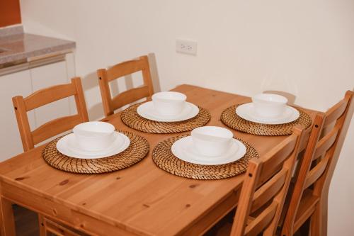 a wooden table with four chairs and white dishes on it at 運河十六 海港景觀整層主臥房Canal16 HarborView Studio in Tainan
