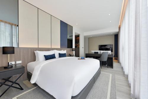 a bedroom with a large white bed and a desk at GM Estate Hotel and Executive Apartments Sukhumvit 20 in Bangkok