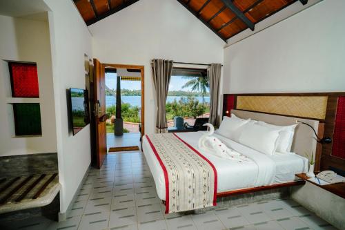 a bedroom with a large bed and a balcony at Vedic Village Retreat Kodungallur in Cochin