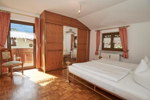 a bedroom with a bed and a chair and windows at Haus Zeitz in Schönau am Königssee