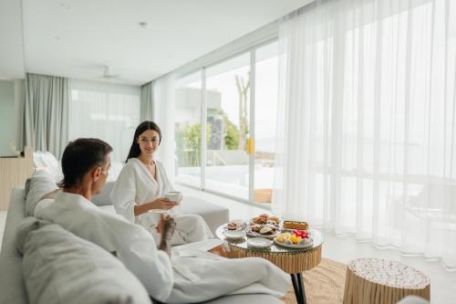 een man en vrouw zittend op een bank in een woonkamer bij Beachfront Secret Tides Villa Luna in Koh Samui 