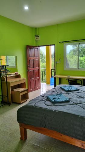 Un dormitorio con una cama y un escritorio y una ventana. en Lanta Ahad Apartments, en Ko Lanta