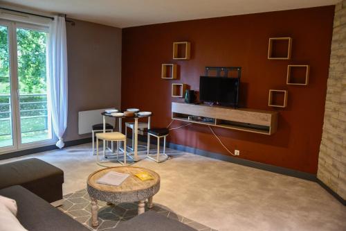 a living room with a couch and a tv at Calme et terrasse privée près de Vichy in Bellerive-sur-Allier