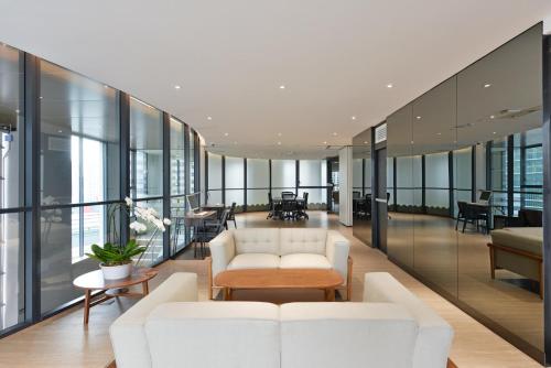 an office lobby with white furniture and glass walls at GM Estate Hotel and Executive Apartments Sukhumvit 20 in Bangkok
