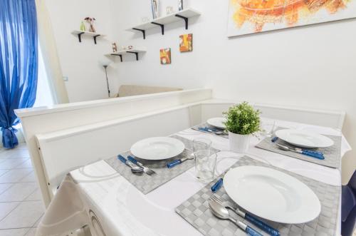Biały stół jadalny z białymi talerzami w obiekcie Residence Elisa Piano Terra con Giardino e Posto Spiaggia Incluso w Caorle