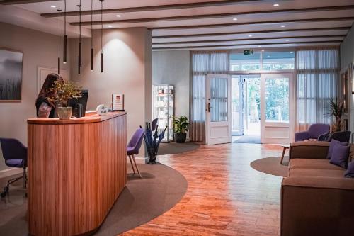 an office lobby with a reception desk and purple chairs at Seehotel Frankenhorst - BW Signature Collection in Schwerin