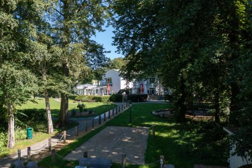 a path through a park with trees and a house at Seehotel Frankenhorst - BW Signature Collection in Schwerin