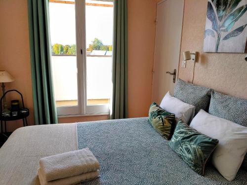 une chambre avec un lit avec des oreillers et une fenêtre dans l'établissement Bel appartement refait à neuf, calme et ensoleillé, à Cabourg