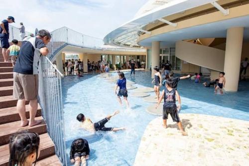 a group of children playing in a swimming pool in a mall at Premiumcourt ChuranoBeach プレミアムコート美ゅらのビーチ in Yaka