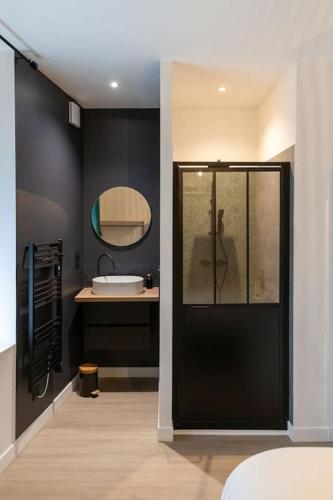 La salle de bains est pourvue d'une porte noire et d'un lavabo. dans l'établissement Le Jungle - Votre séjour tout confort - Fibre, à Châteauroux