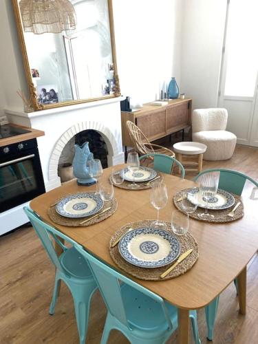 une table en bois avec des assiettes et des verres à vin dessus dans l'établissement Apt lumineux 2 chambres, à 2 min de la plage, à Le Touquet-Paris-Plage