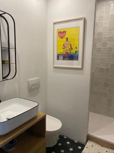 La salle de bains est pourvue d'un lavabo, de toilettes et d'une photo. dans l'établissement Apt lumineux 2 chambres, à 2 min de la plage, à Le Touquet-Paris-Plage