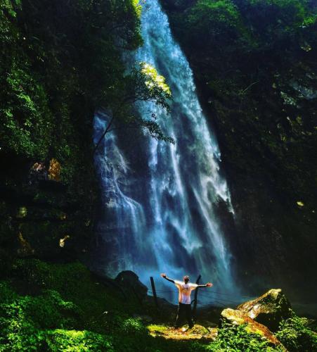a man standing in front of a waterfall at Little Forest Homestay in Gushaini