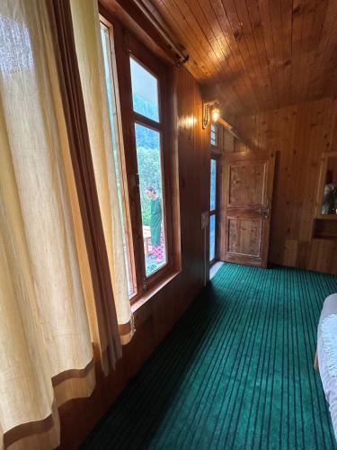an empty room with a window and green floor at Little Forest Homestay in Gushaini
