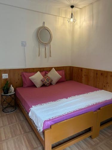 a bed with pink and white sheets and a mirror at Little Forest Homestay in Gushaini