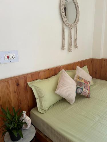 a bed with pillows and a mirror on the wall at Little Forest Homestay in Gushaini