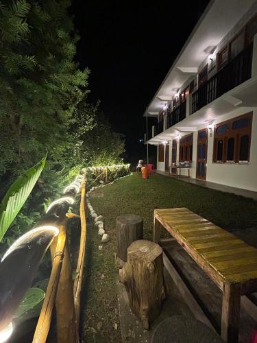 a wooden bench next to a building at night at Little Forest Homestay in Gushaini