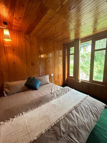 a bedroom with a large bed in a wooden wall at Little Forest Homestay in Gushaini
