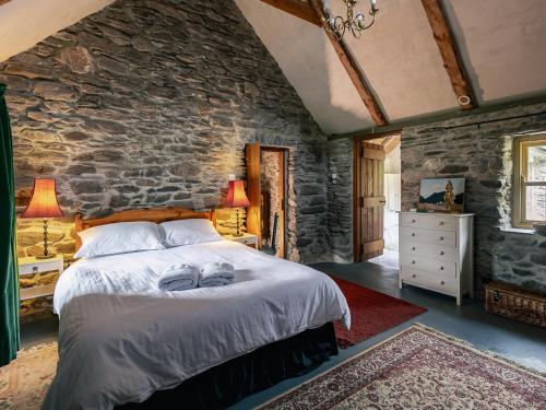 a bedroom with a bed and a stone wall at Traditional style thatched cottage in Kenmare in Kenmare