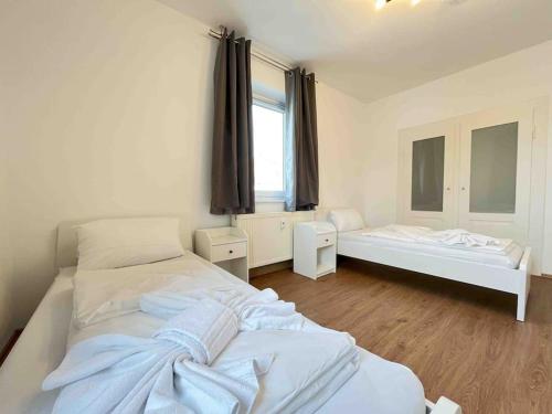 a white bedroom with two beds and a window at SAD232 - Moderne Monteurwohnung Übergangswohnung in Schwandorf in Bayern