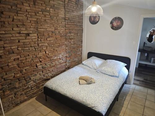 - une chambre avec un mur en briques et un lit avec un chapeau dans l'établissement L'Aristide proche gare parking facile, à Montauban