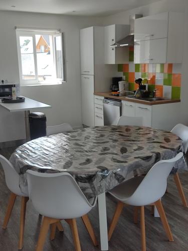 une cuisine avec une table, des chaises blanches et une table. dans l'établissement Escapade Normande, à Goderville