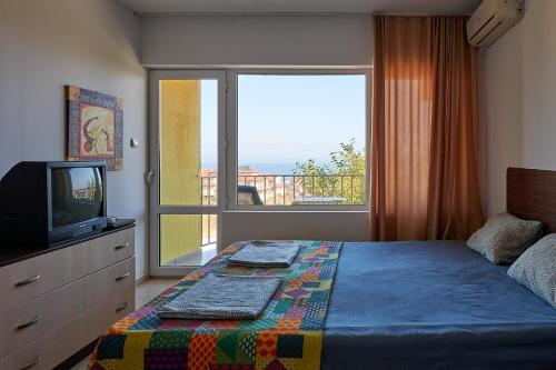 a bedroom with a bed and a television and a balcony at Guest House Dima in Sozopol
