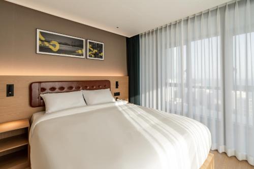 a bedroom with a large white bed and a window at D OV Haeundae Hotel in Busan