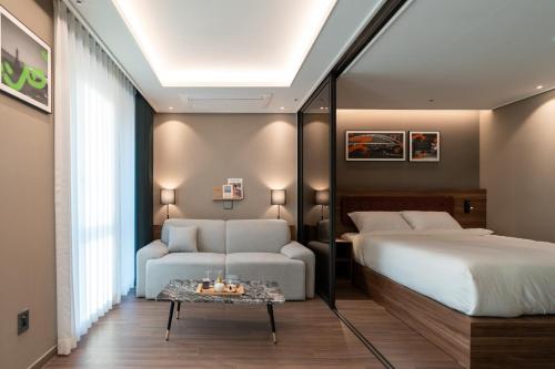 a bedroom with a bed and a couch and a table at D OV Haeundae Hotel in Busan