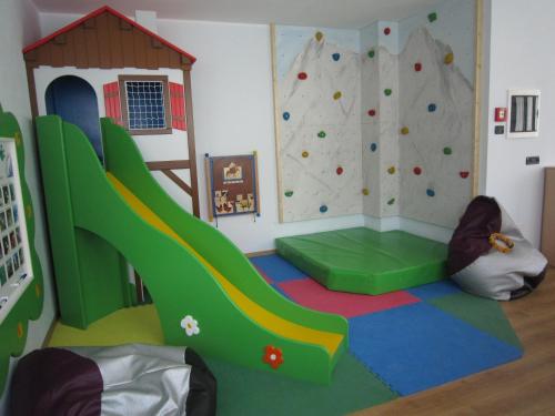a play room with a slide and a climbing wall at Tevini Dolomites Charming Hotel in Commezzadura