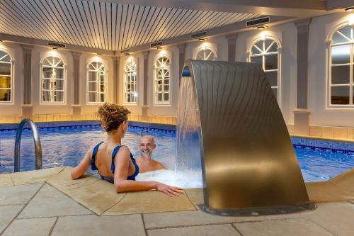 a man and a woman in a swimming pool at Hotel Quartier Latin in Marche-en-Famenne