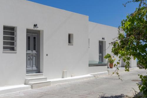 a white house with a black door and stairs at South Akro in Míthoi