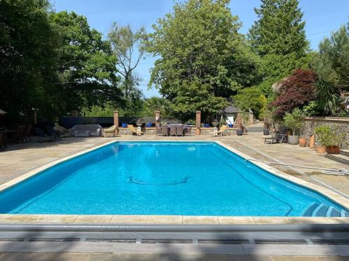 Una piscina con agua azul en un patio. en 4 bedroom Lodge Hotub-Pool in Surrey UK, en East Horsley