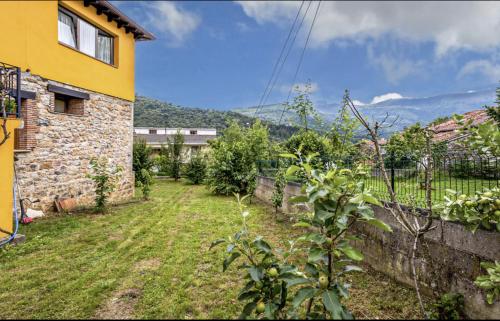 un patio trasero con una pared de piedra y una casa en La Tienda de Abajo - Apartamentos acogedores con calefacción, parking y vistas al Valle de Soba, en Villar