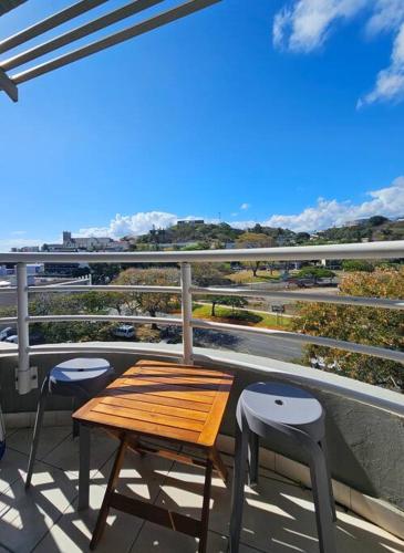 a wooden table and two stools on a balcony at F2en duplex tout équipé arrivée autonome in Noumea